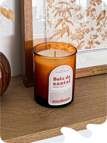 Bougie parfumée bois de santal en verre ambré, posée sur une étagère en bois dans une décoration naturelle et chaleureuse.