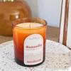Bougie parfumée cannelle en verre ambré, posée sur un plateau en céramique dans un intérieur chaleureux.