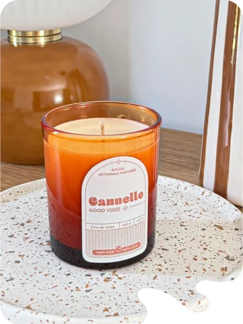 Bougie parfumée cannelle en verre ambré, posée sur un plateau en céramique dans un intérieur chaleureux.