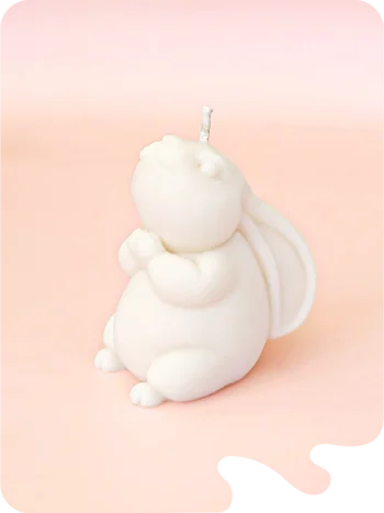 Bougie artisanale en forme de lapin, couleur blanche, sur fond rose. Une touche poétique et apaisante pour votre intérieur.