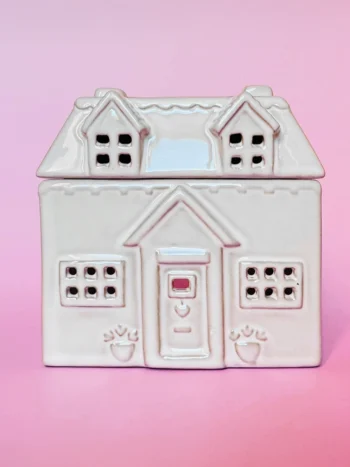 Brûle-parfum en céramique en forme de maison cottage, vue de face, avec des détails sculptés, fenêtres et porte ajourées.