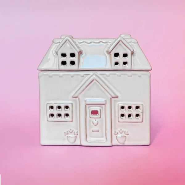 Brûle-parfum en céramique en forme de maison cottage, vue de face, avec des détails sculptés, fenêtres et porte ajourées.