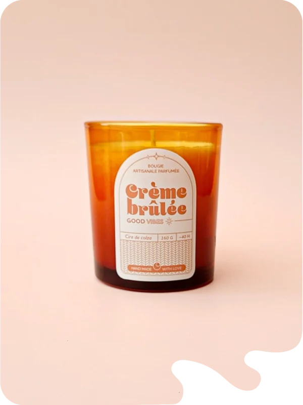 Bougie artisanale parfumée senteur crème brûlée, coulée dans un verre ambré avec une étiquette vintage – une touche chaleureuse et gourmande pour une ambiance cocooning.