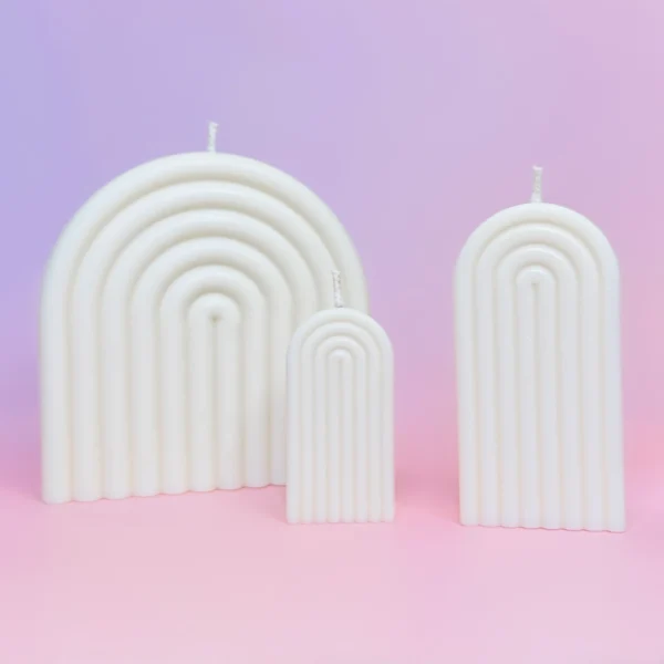 Trio de bougies Happy Arche sculptées en forme d’arche, de couleur blanche, disposées sur un fond rose et violet pour une ambiance douce et moderne.