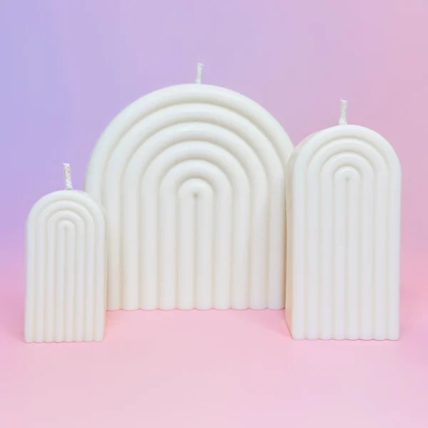 Trio de bougies Happy Arche en cire naturelle, design moderne en forme d’arche, sur fond rose et violet pour une décoration élégante et minimaliste.