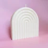 Bougie sculptée Happy Arche taille L en cire naturelle, design minimaliste et élégant, posée sur un fond rose pour une ambiance douce et moderne.