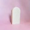 Bougie sculptée Happy Arche taille M en cire naturelle, design minimaliste et élégant, sur fond rose pour une décoration douce et apaisante.