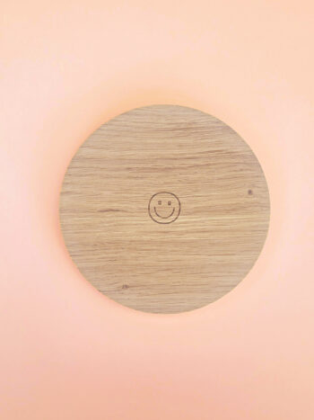 Support rond en bois naturel avec smiley gravé, conçu pour accueillir bougies décoratives ou parfumées, présenté sur fond pastel.