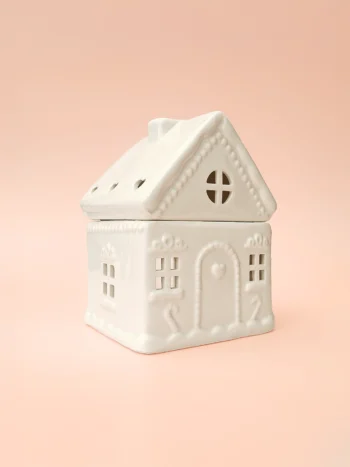 Brûle-parfum Sugar House en céramique blanche, design maison de pain d’épices, vue de trois-quarts sur fond rose.