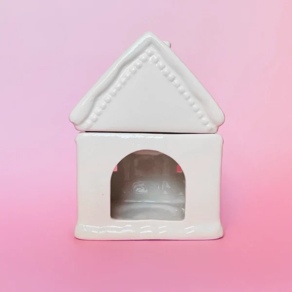 Brûle-parfum Sugar House en céramique blanche, vue arrière avec ouverture pour insérer une bougie chauffe-plat, sur fond rose.