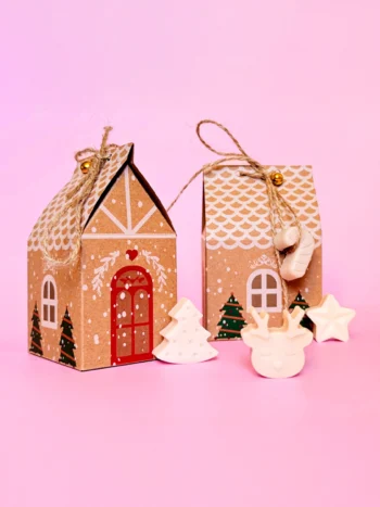 Pack de 5 fondants parfumés en forme de sapin, étoile et renne, présentés dans des maisons en carton décorées pour Noël.