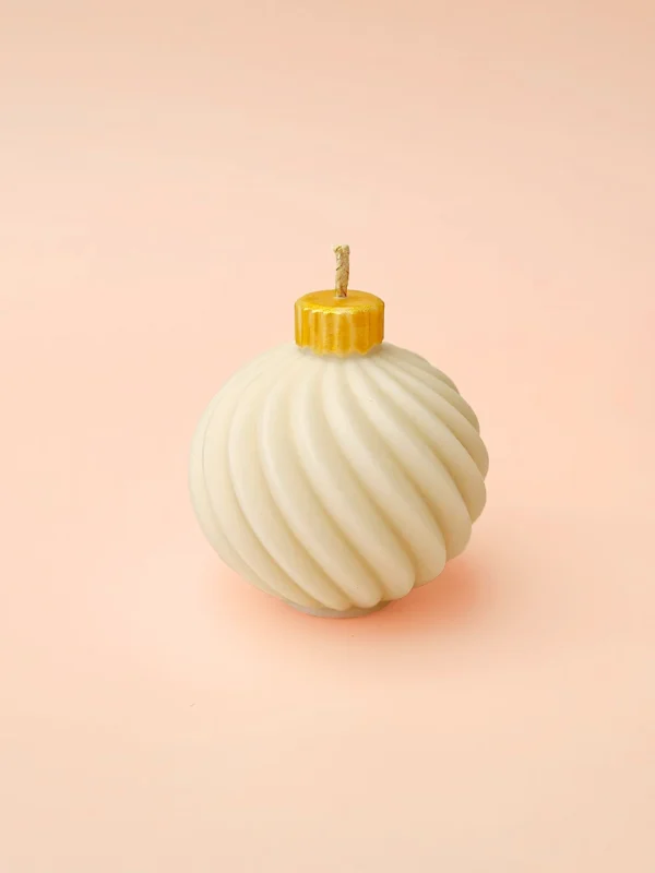 Bougie décorative Bubble Glow en cire naturelle, forme boule torsadée avec capuchon doré, présentée sur fond rose pastel.