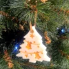 Suspension en cire parfumée en forme de sapin avec détails dorés, accrochée dans un arbre de Noël.