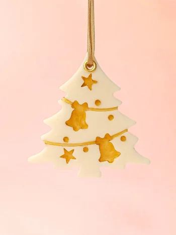 Suspension parfumée Pimp My Tree en forme de sapin, décorée de détails dorés, parfum sapin de Noël, présentée sur fond rose pastel.