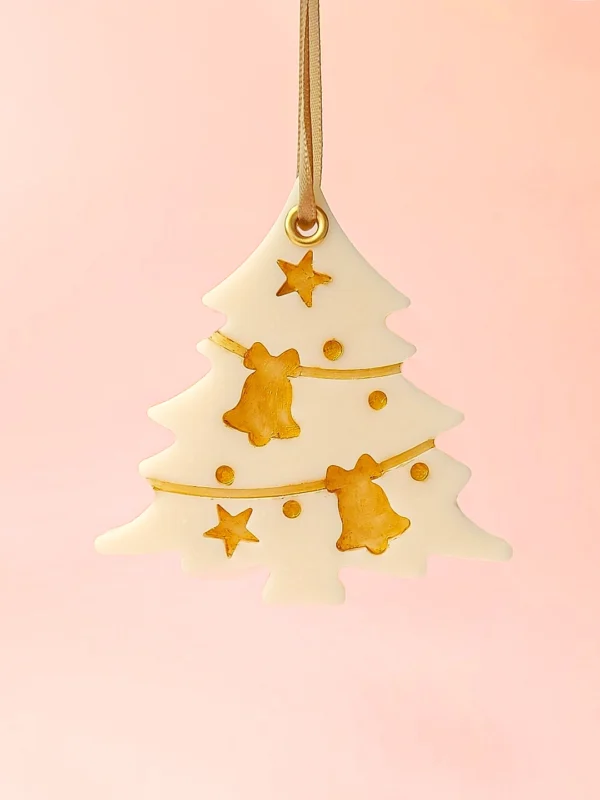 Suspension parfumée Pimp My Tree en forme de sapin, décorée de détails dorés, parfum sapin de Noël, présentée sur fond rose pastel.
