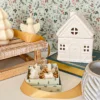 Brûle-parfum Sugar House en céramique blanche, présenté avec des décorations de Noël et une boîte de fondants parfumés.