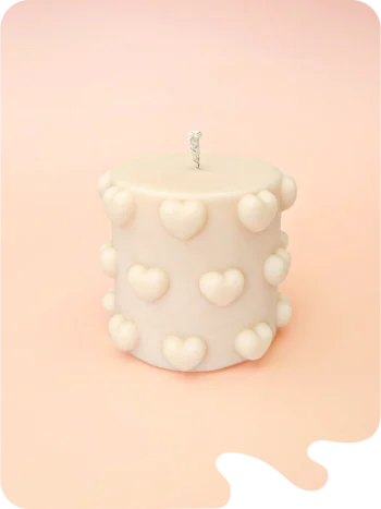 Bougie décorative Little Crush en cire naturelle, format cylindrique compact avec cœurs en relief, couleur ivoire, présentée sur fond pastel.